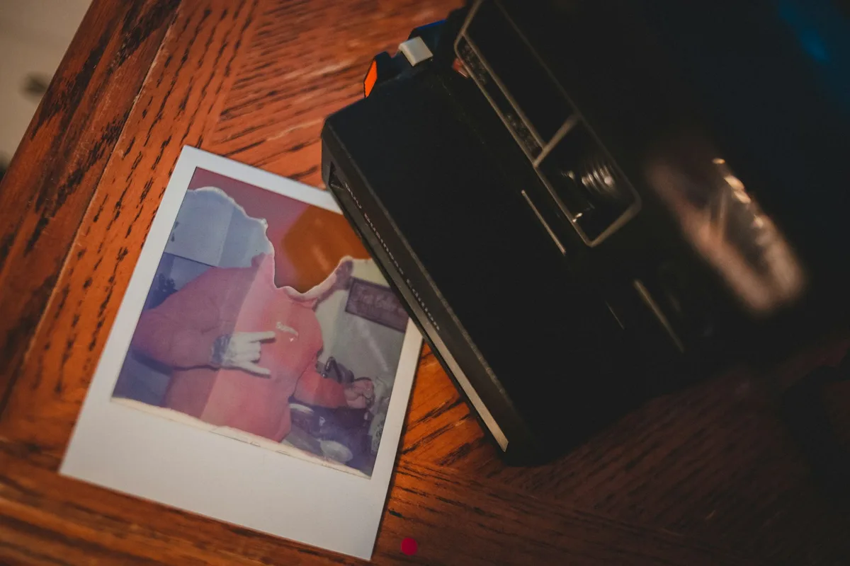 Pile de photos imprimées posée sur un bureau à côté d'un appareil photo et d'un téléphone