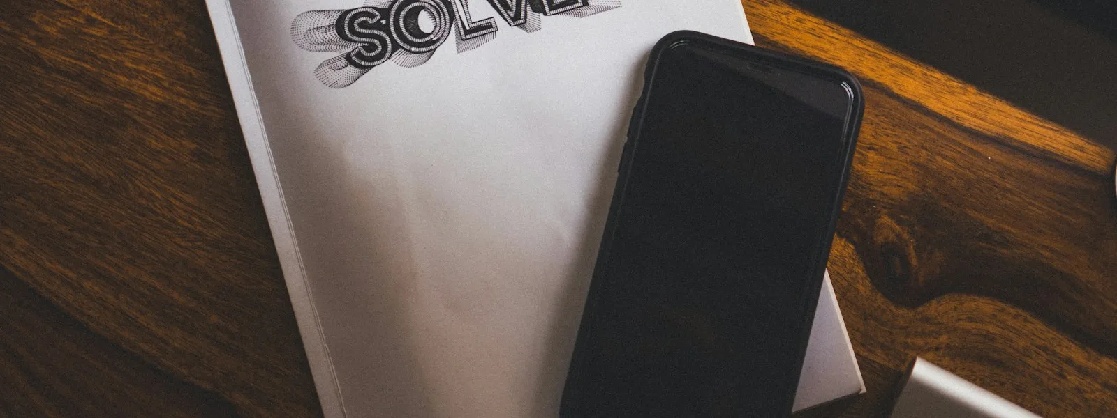 Téléphone posé sur une table en bois affichant un fil d'actualité flouté à côté d'un carnet