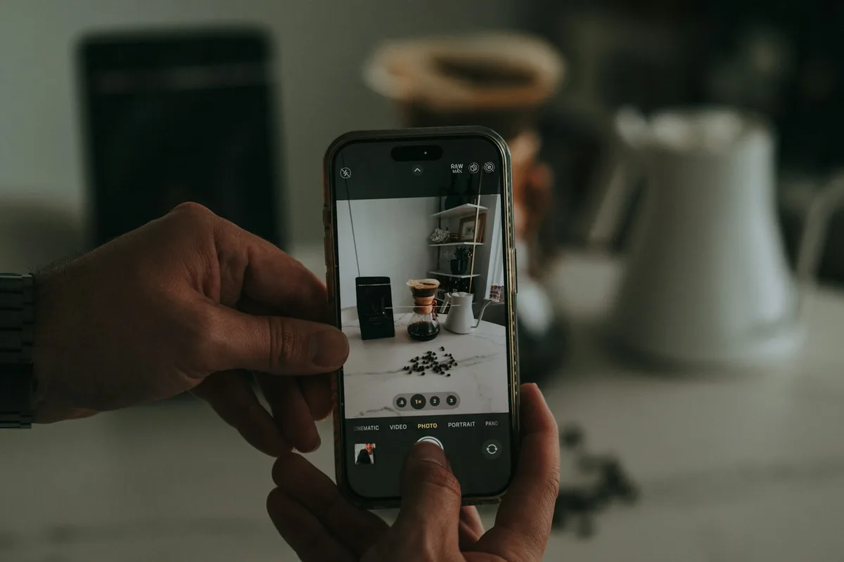 Mains photographiant au téléphone une petite mise en scène de produits sur un comptoir