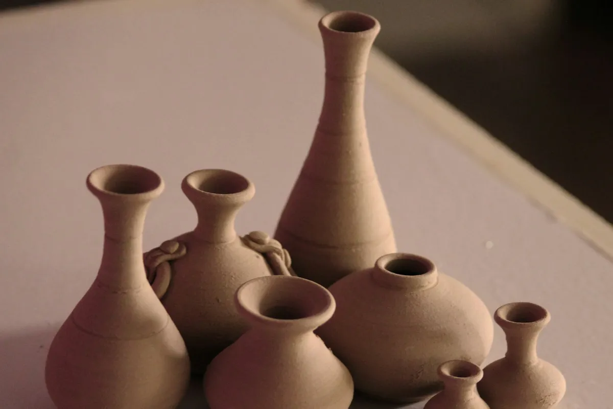 Des vases en terre cuite terminés, alignés sur l'établi d'un atelier