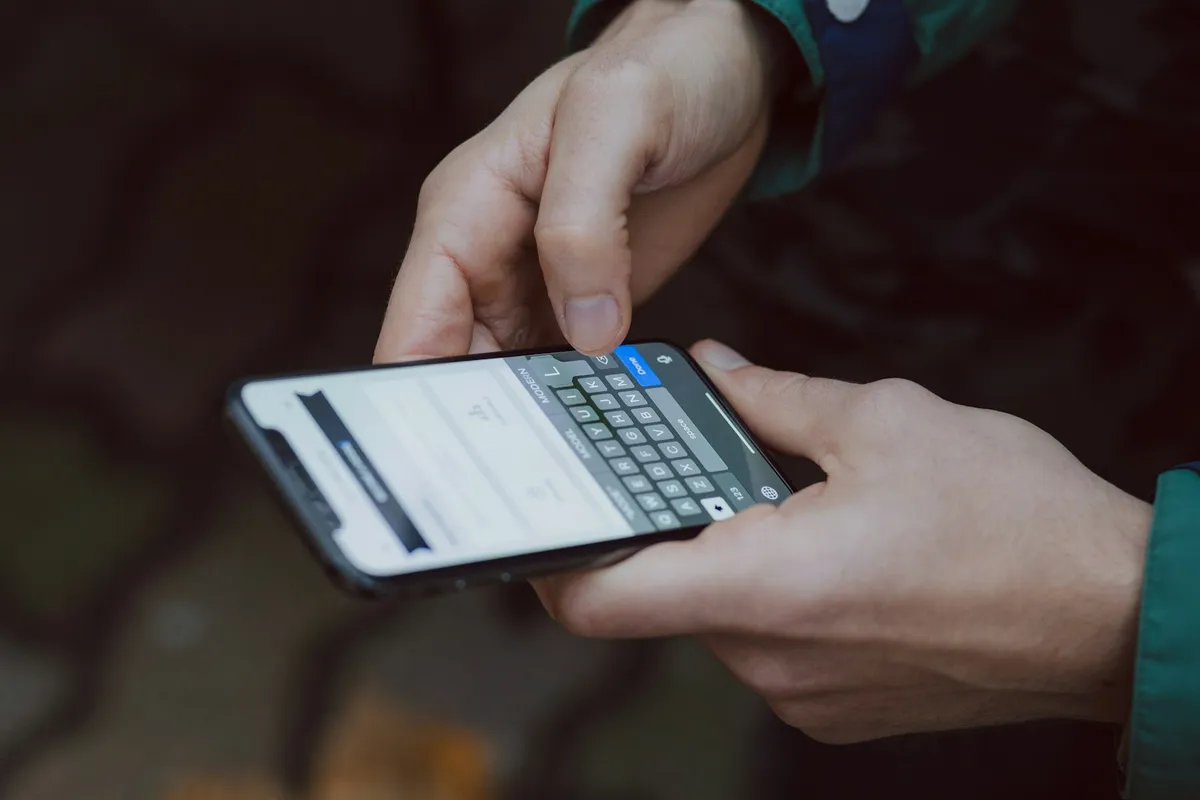 Deux mains tapent un message sur le clavier d'un téléphone