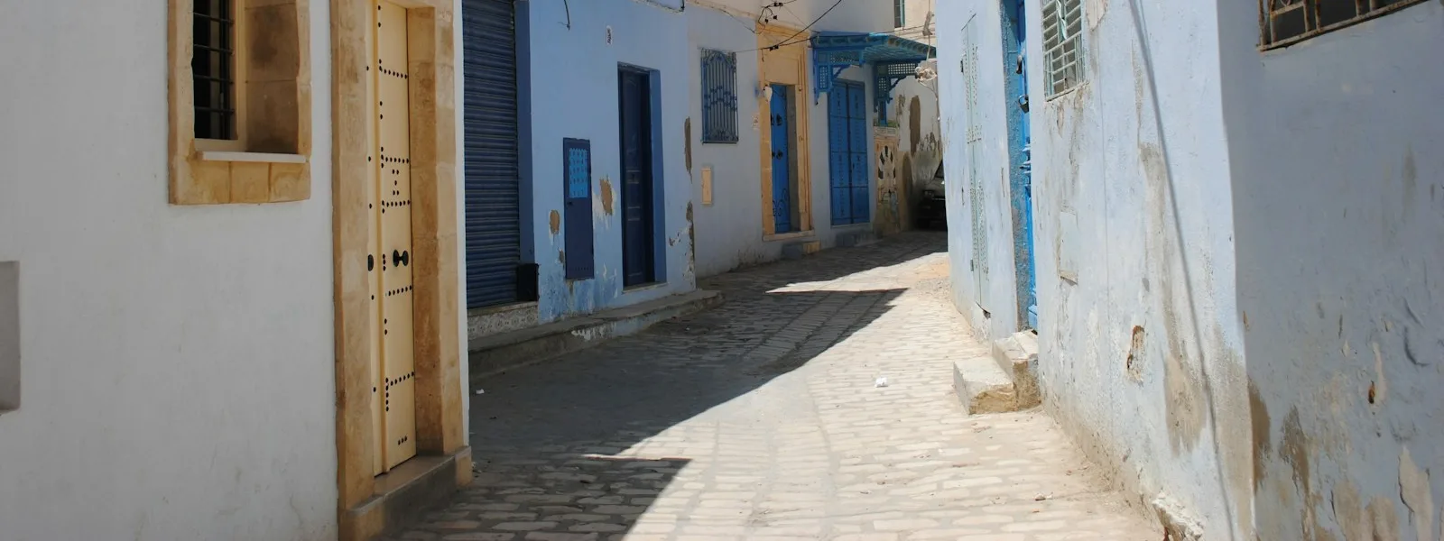 Ruelle de la médina de Sousse bordée de façades blanches et de portes bleues