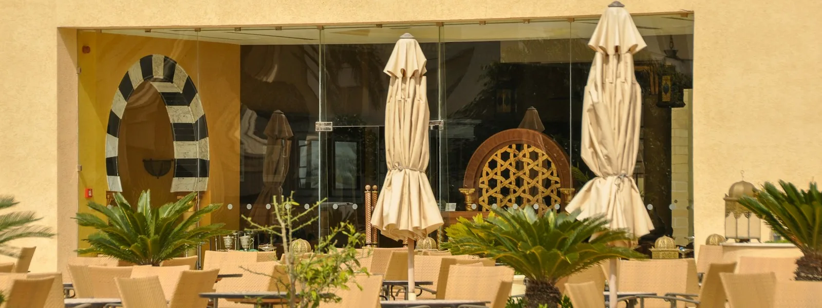 Terrasse de café tunisienne aux tables vides, prête à accueillir les clients du jour