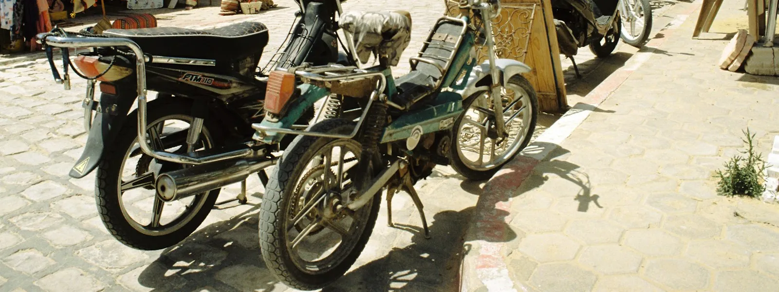 Motos garées devant les boutiques d'une rue commerçante tunisienne en plein soleil