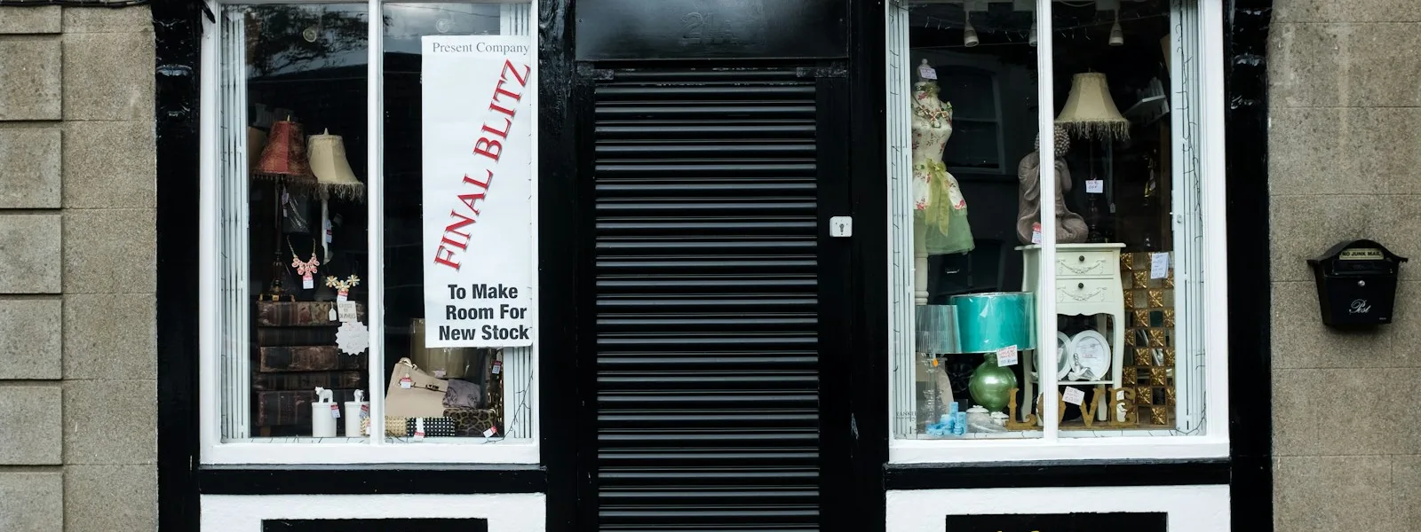 La devanture d'une boutique de quartier, enseigne peinte et vitrines éclairées
