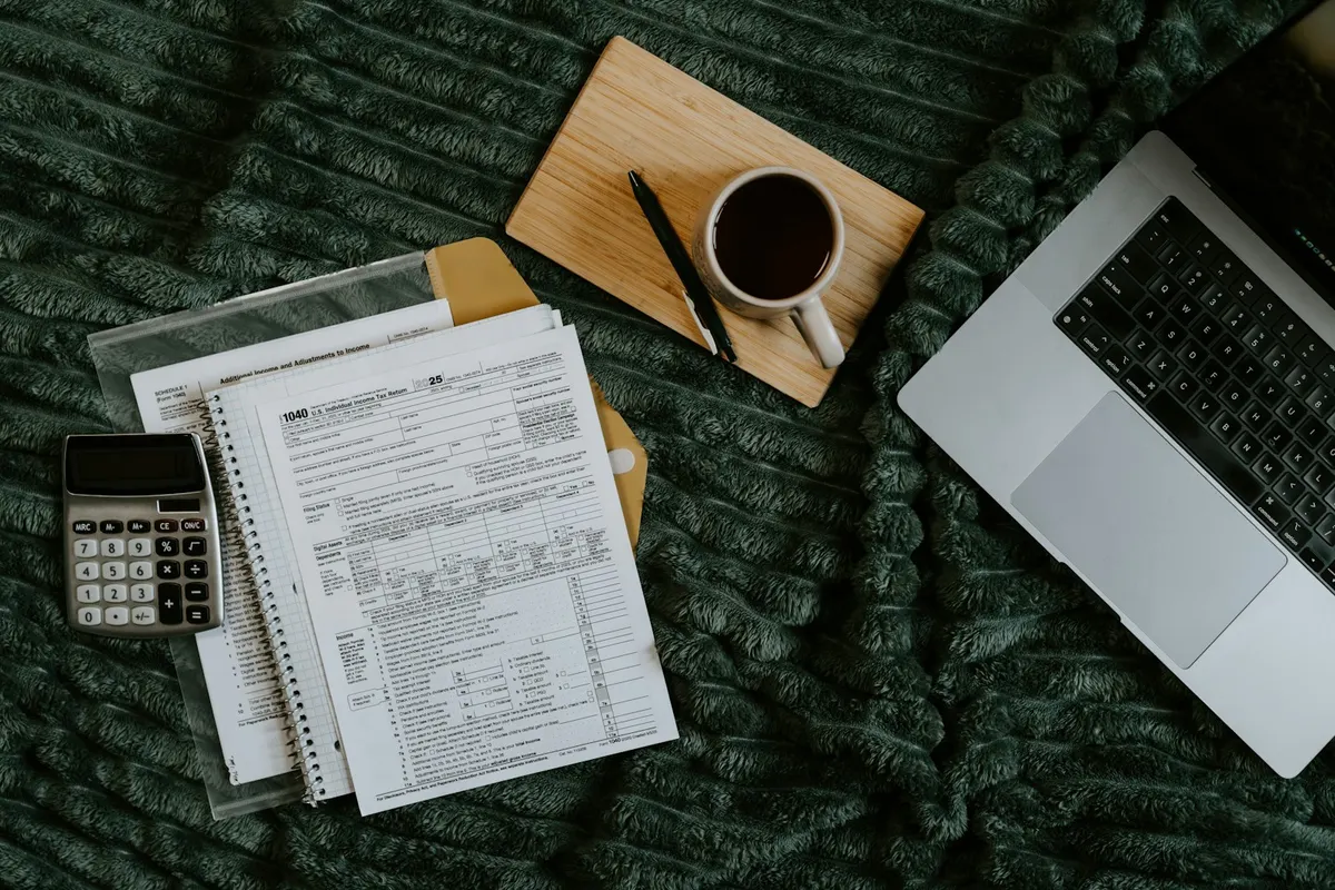 Documents imprimés, calculatrice et ordinateur portable posés côte à côte pour vérification
