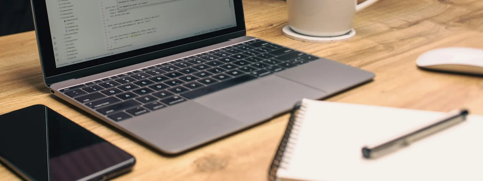 Un téléphone et un carnet ouvert posés près d'un ordinateur portable sur un bureau