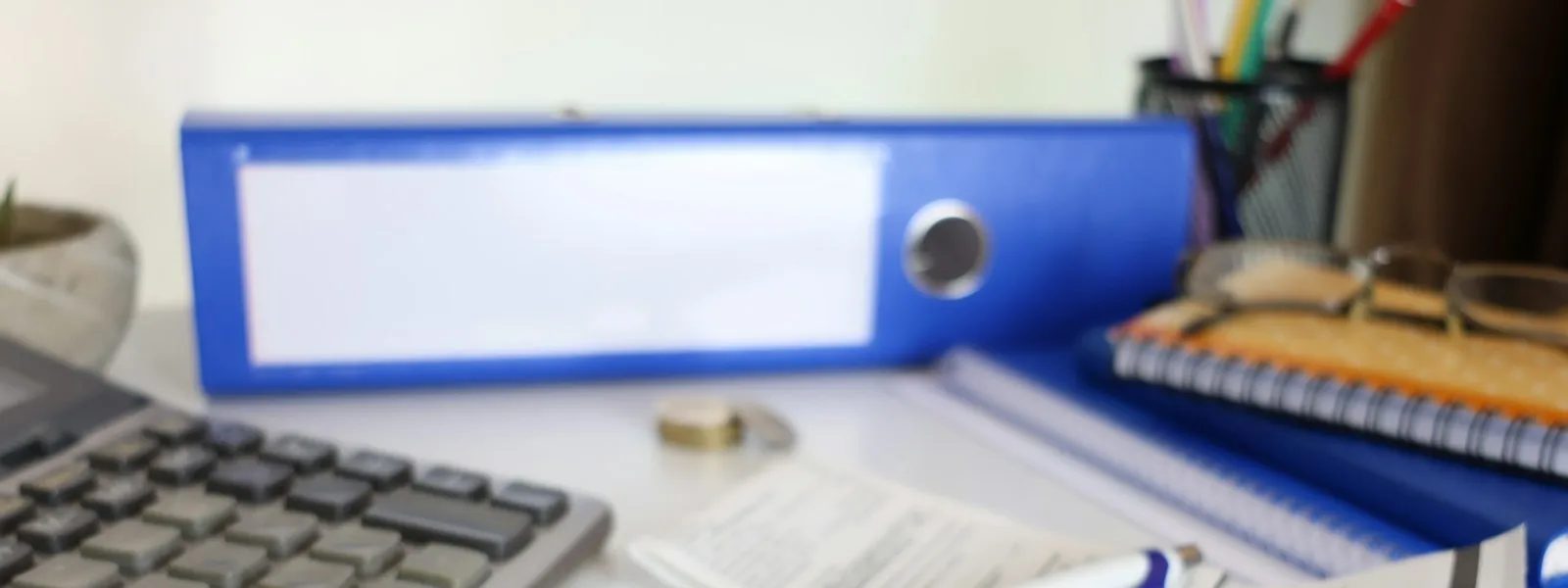 Une calculatrice, un classeur et des papiers posés près d'un clavier sur un bureau