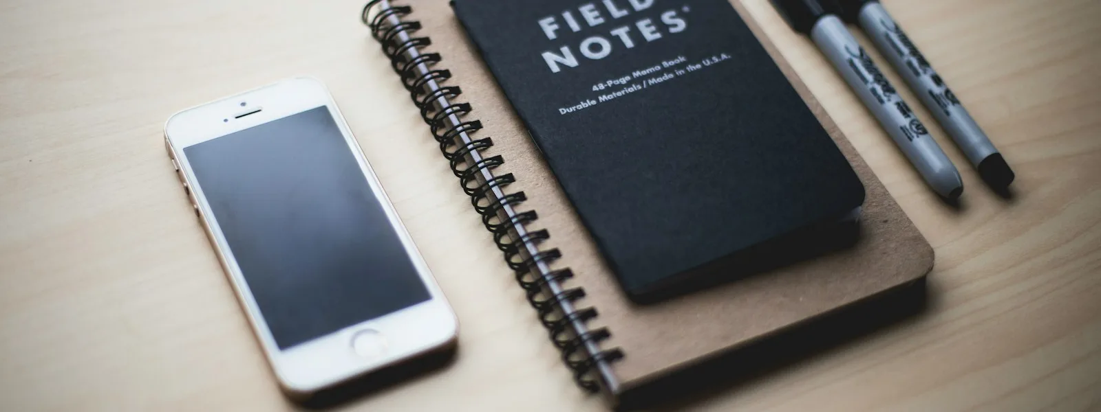 Un téléphone posé à côté de carnets et de stylos sur un bureau