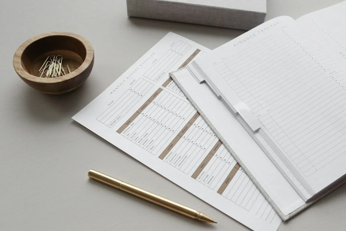 Des feuilles de planification aux champs vides et un stylo doré posés sur un bureau