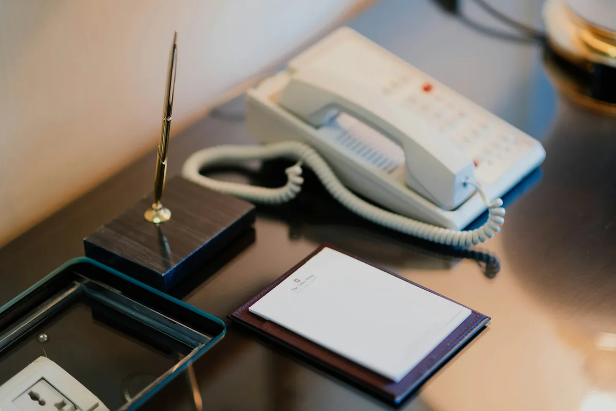 Carnet d'appels manuscrit posé à côté d'un téléphone de bureau