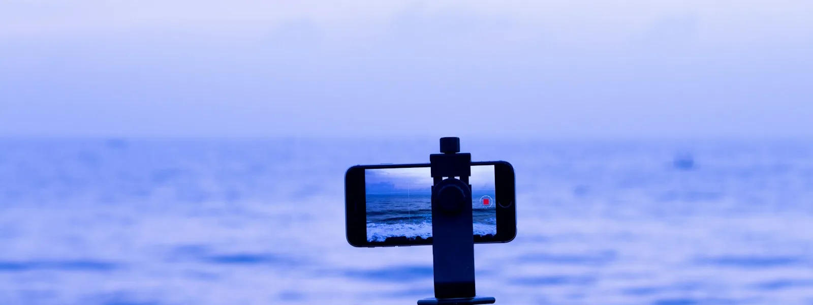 Un téléphone fixé sur un mini trépied filme la mer en cadrage vertical