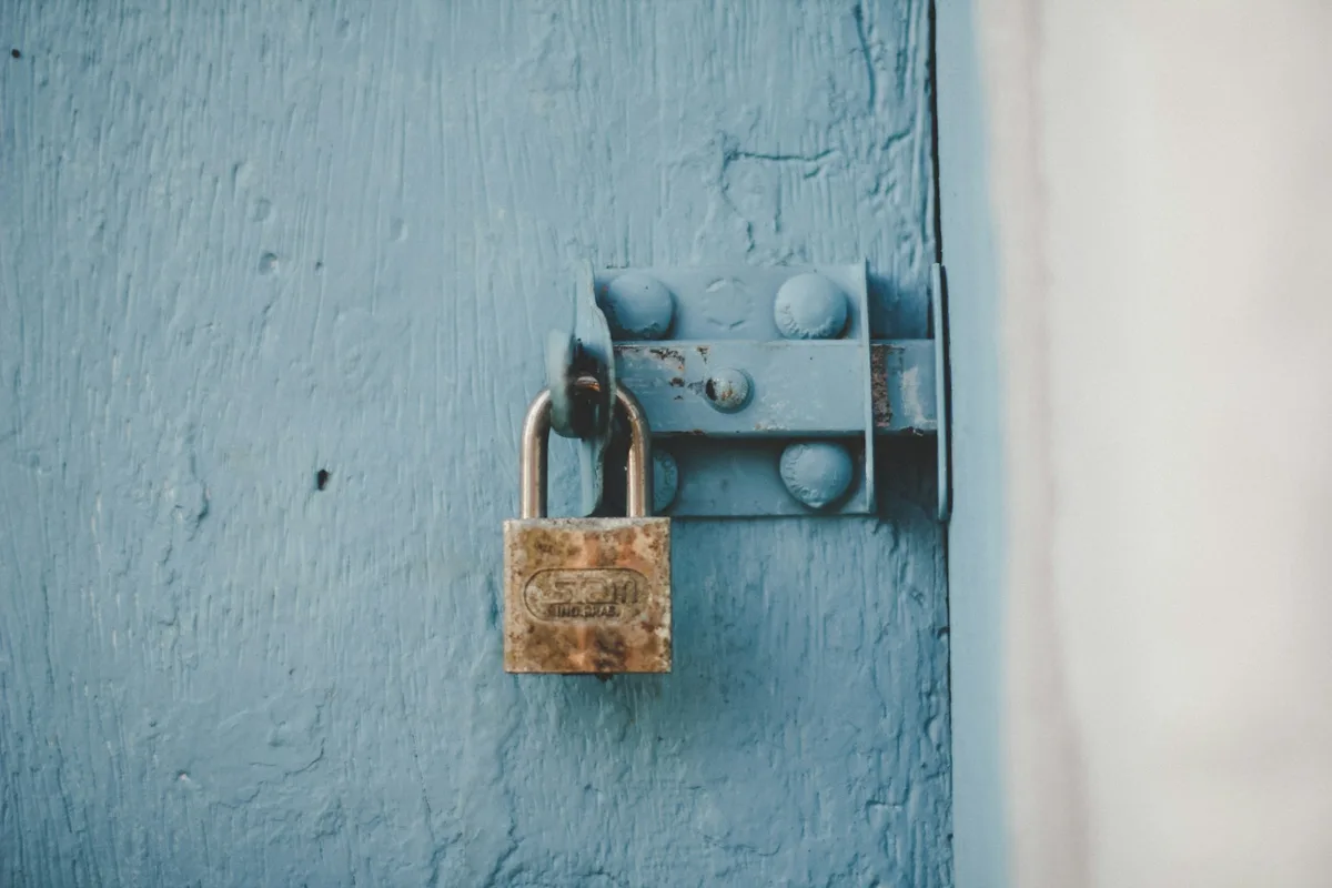 Un cadenas ancien sur une porte en bois peinte en bleu, détail serré