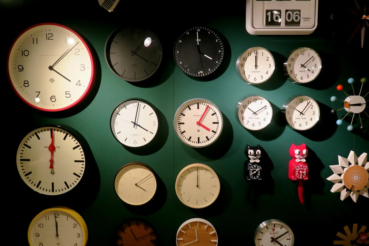 Un mur couvert d'horloges affichant chacune une heure différente