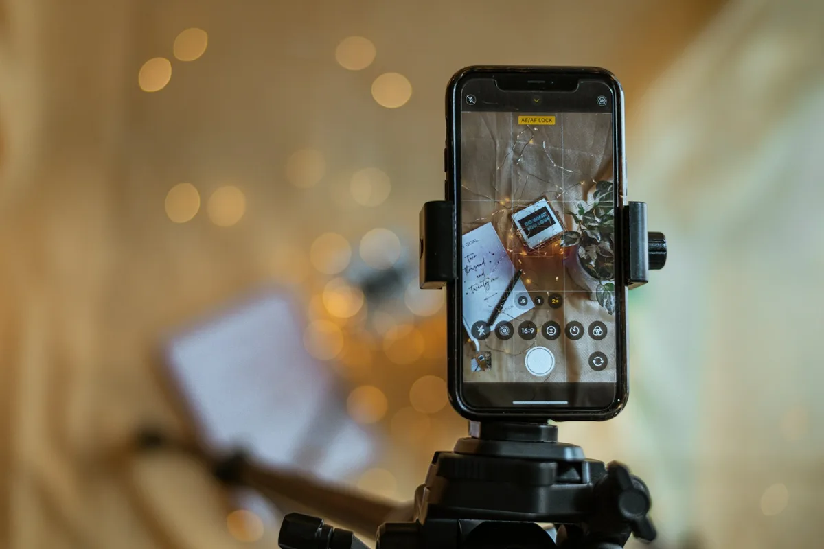 Téléphone sur trépied photographiant un produit artisanal devant une fenêtre