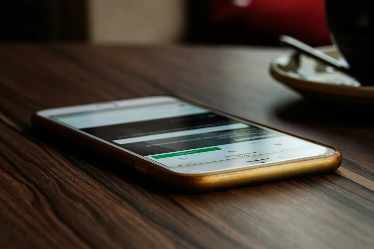 Écran de téléphone affichant une conversation de messagerie anonymisée posée sur un bureau