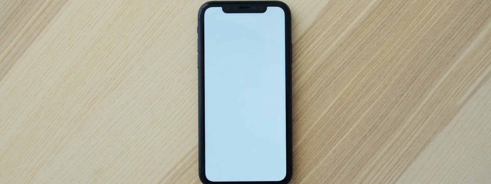 Téléphone posé sur une table affichant une landing page simple avec un titre et un bouton