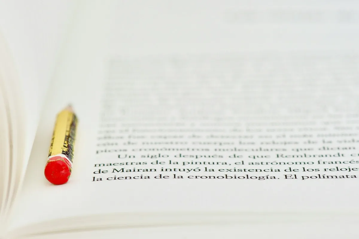 Crayon rouge posé sur une page de texte imprimé, prêt à rayer