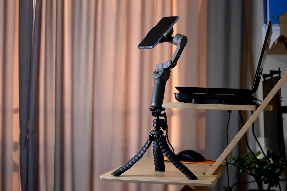 Un téléphone monté sur trépied flexible, posé près d'une fenêtre pour filmer