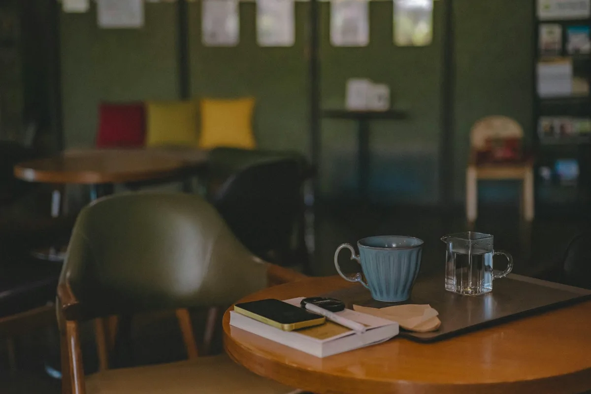Une table de café avec deux tasses, un carnet fermé et un téléphone