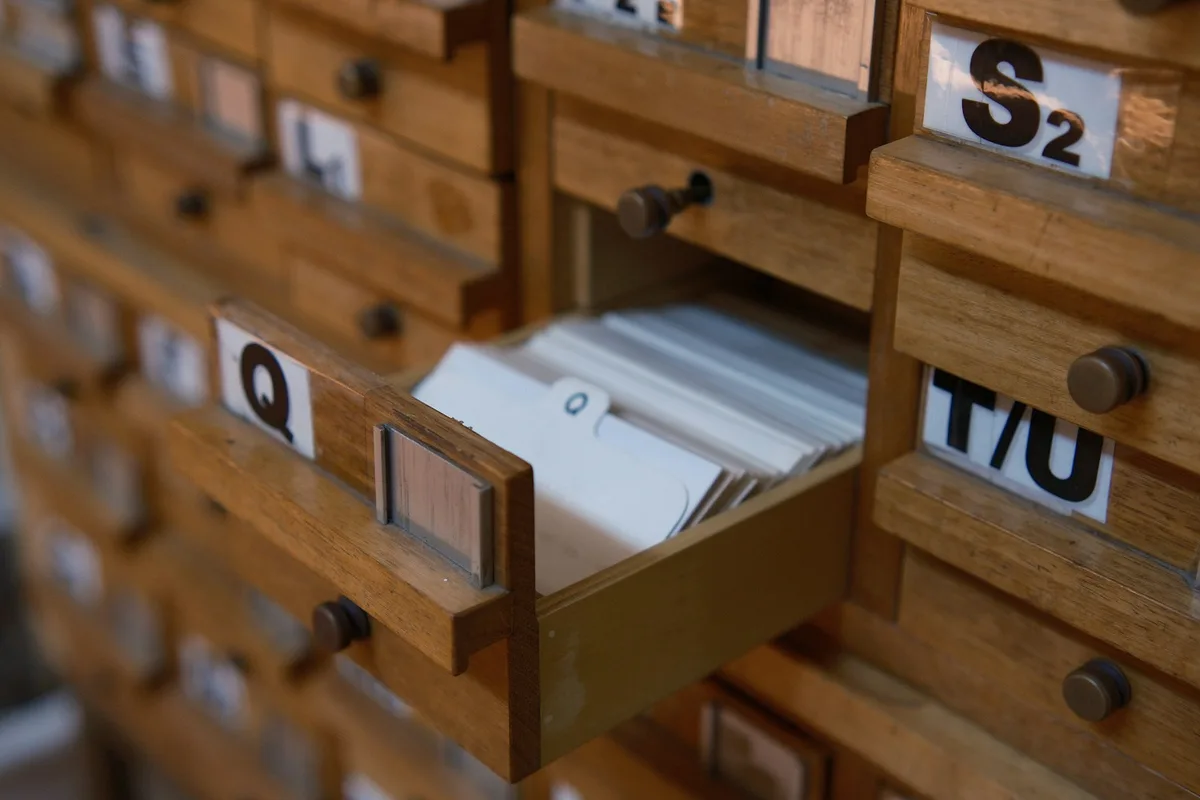 Classeur de fiches cartonnées ouvert sur des onglets alphabétiques posé sur un bureau