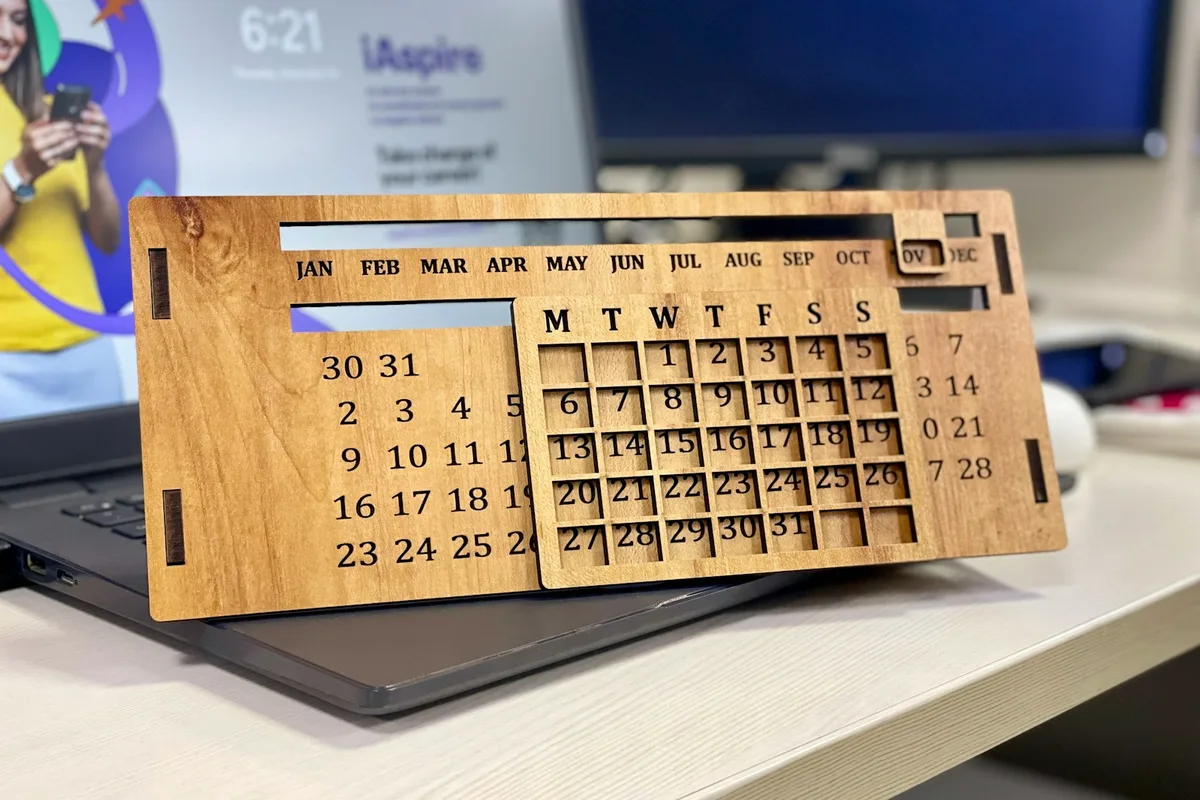 Un calendrier en bois posé sur un ordinateur portable, sur un bureau