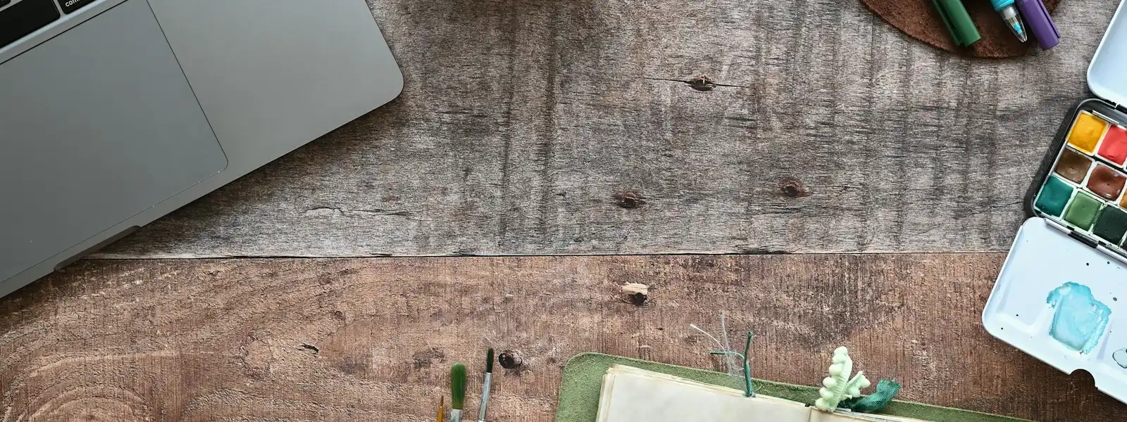 Un ordinateur portable ouvert près d'un carnet annoté et d'un téléphone
