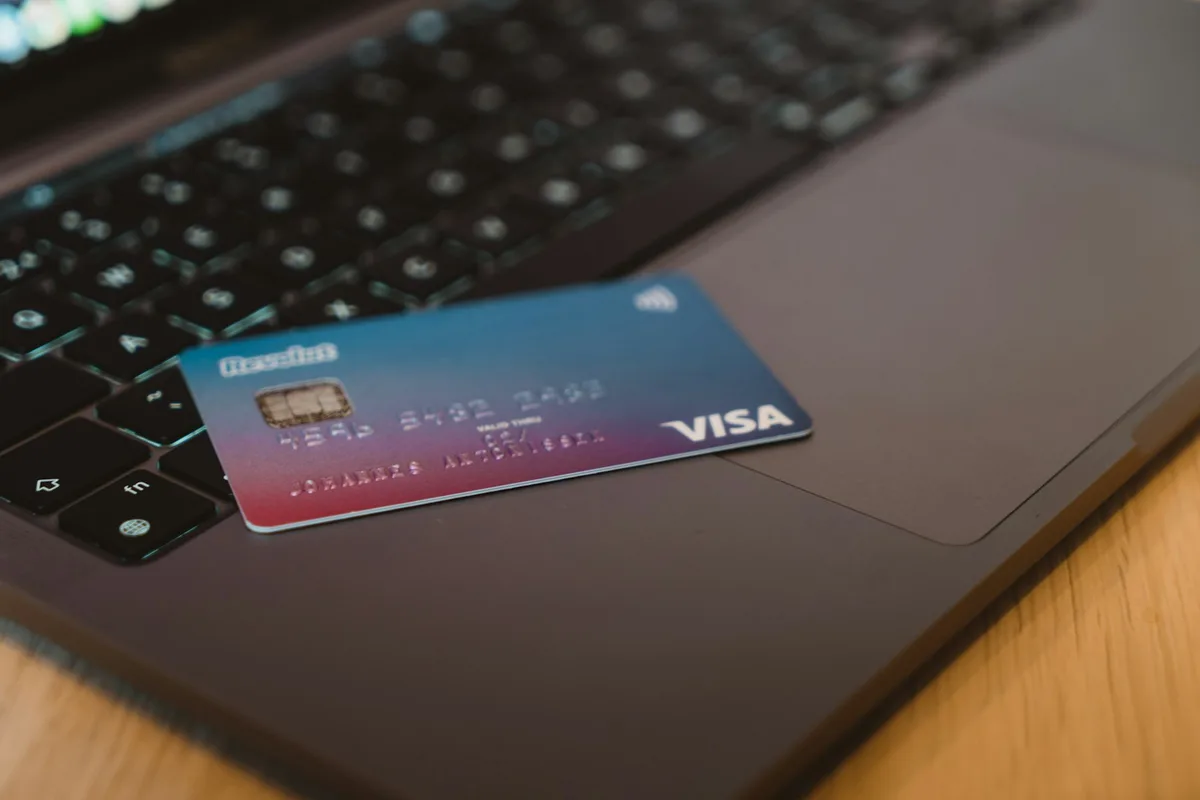 Une carte bancaire posée sur le clavier d'un ordinateur portable, numéros illisibles