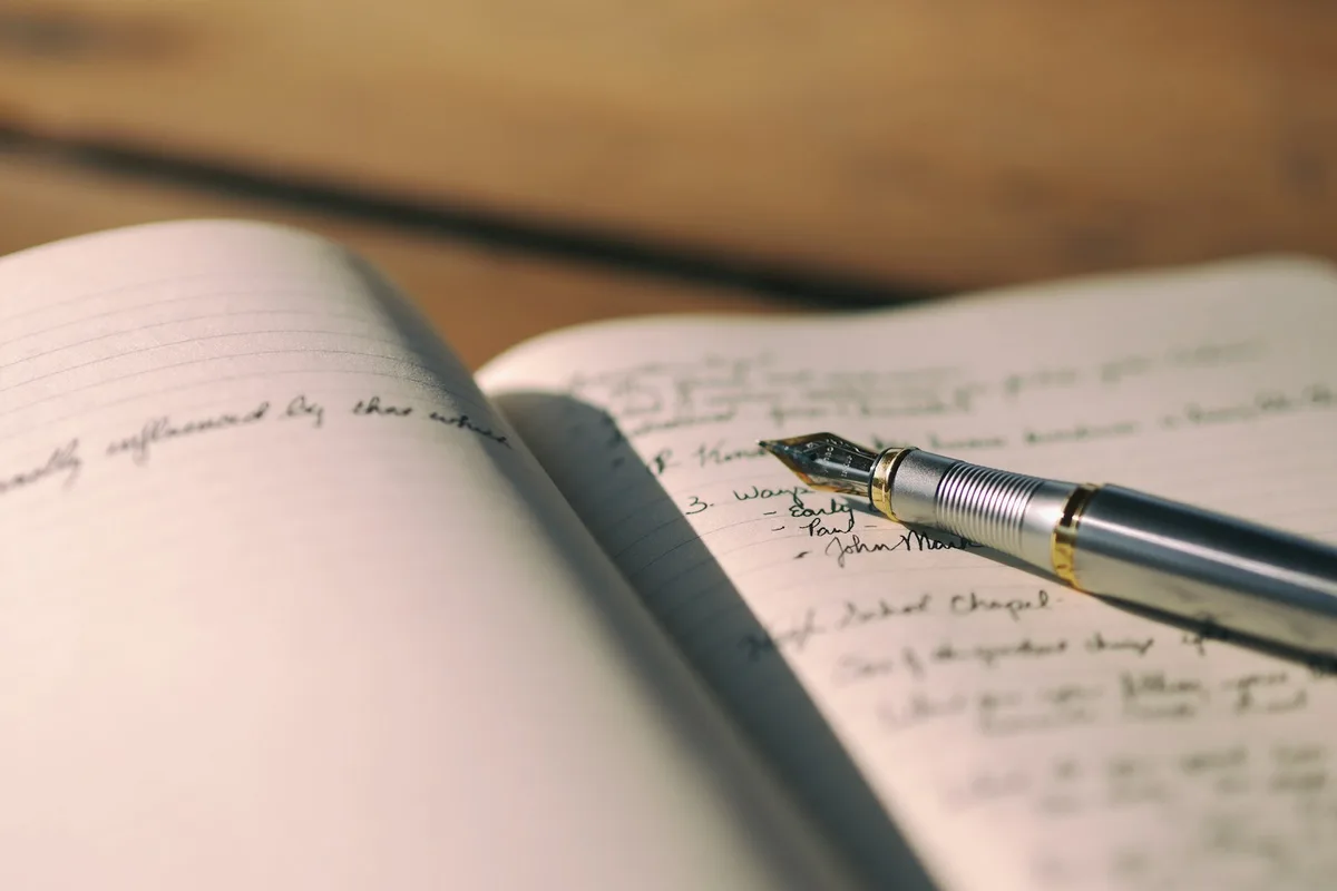 Carnet à spirale ouvert sur une liste manuscrite avec un stylo posé dessus