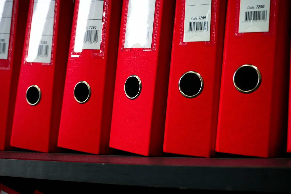 Classeur ouvert avec des intercalaires colorés séparant des documents rangés