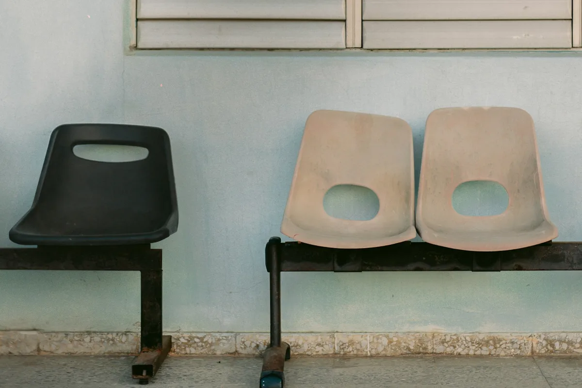 Salle d'attente vide avec trois chaises alignées et des revues posées sur une table basse