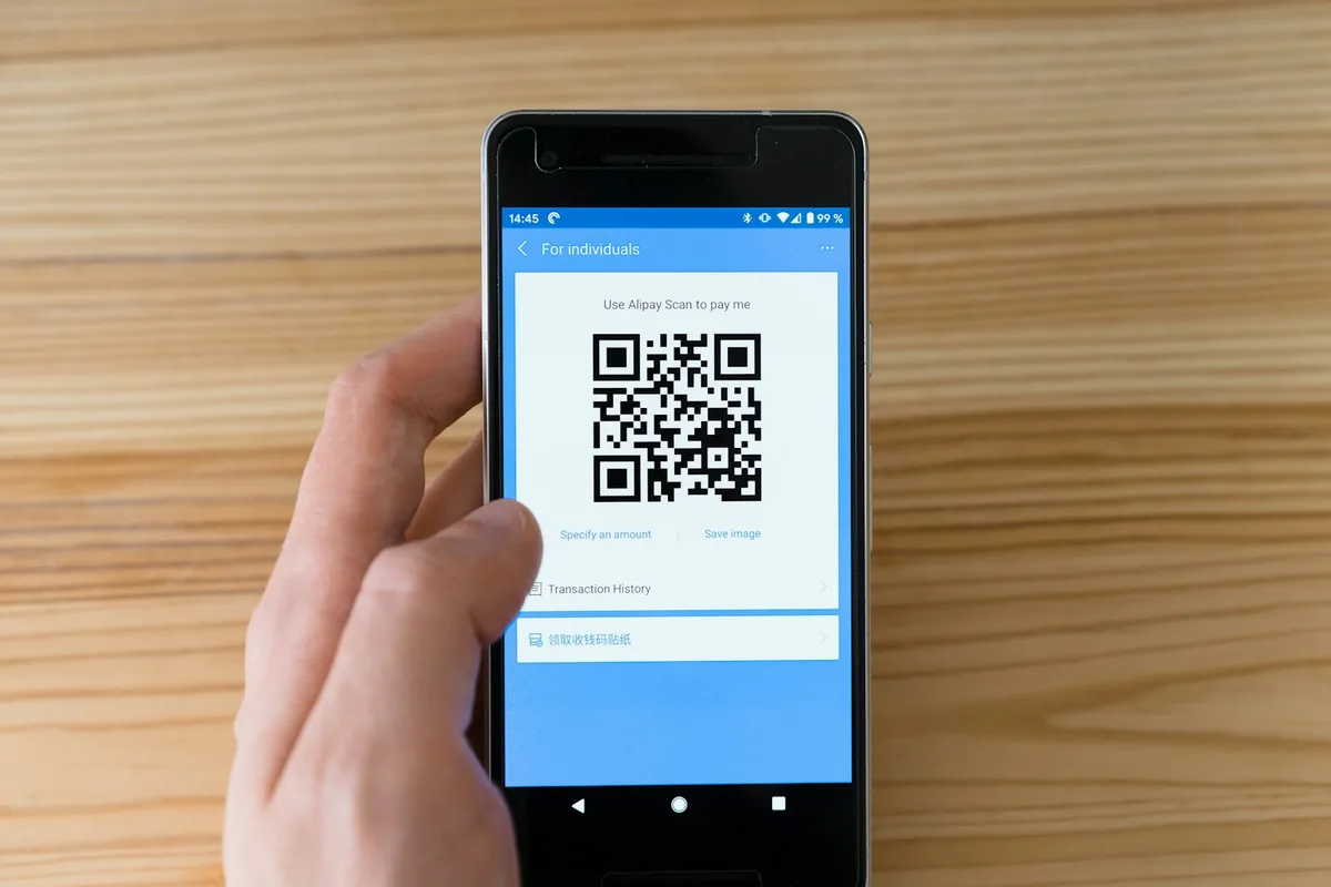 Téléphone tenu en main affichant un QR code de suivi à scanner