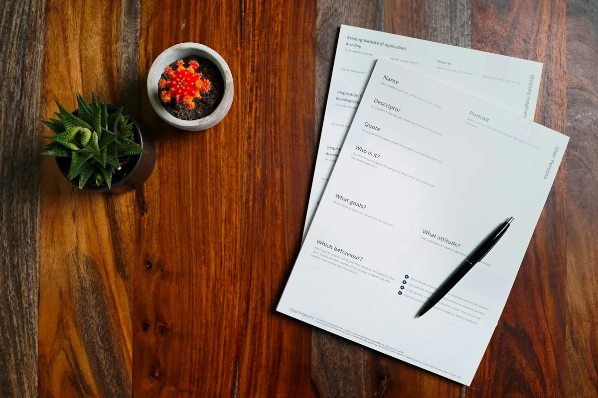 Des formulaires imprimés et un stylo posés sur une table en bois foncé