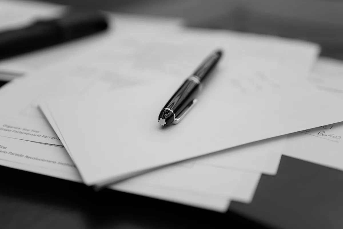 Stylo posé sur une pile de documents imprimés, prêts pour une relecture attentive