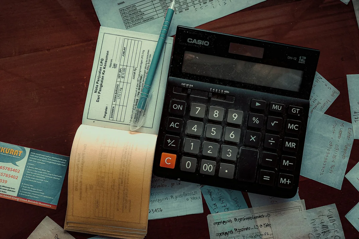 Une calculatrice posée sur un carnet de reçus et des tickets étalés sur une table