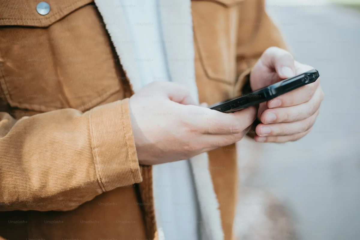 Mains tenant un téléphone et tapant un message, visage hors du cadre