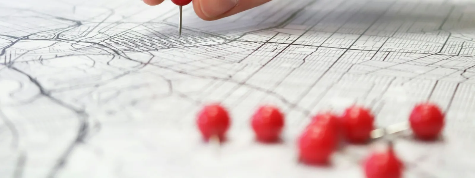 Des punaises rouges posées une à une sur un plan de ville
