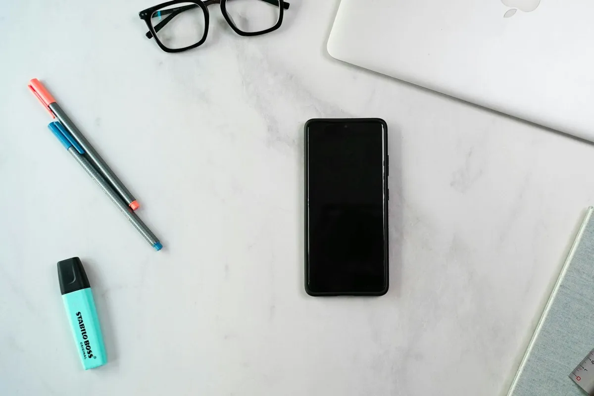 Un ordinateur portable, un carnet, un stylo et des lunettes posés sur un bureau