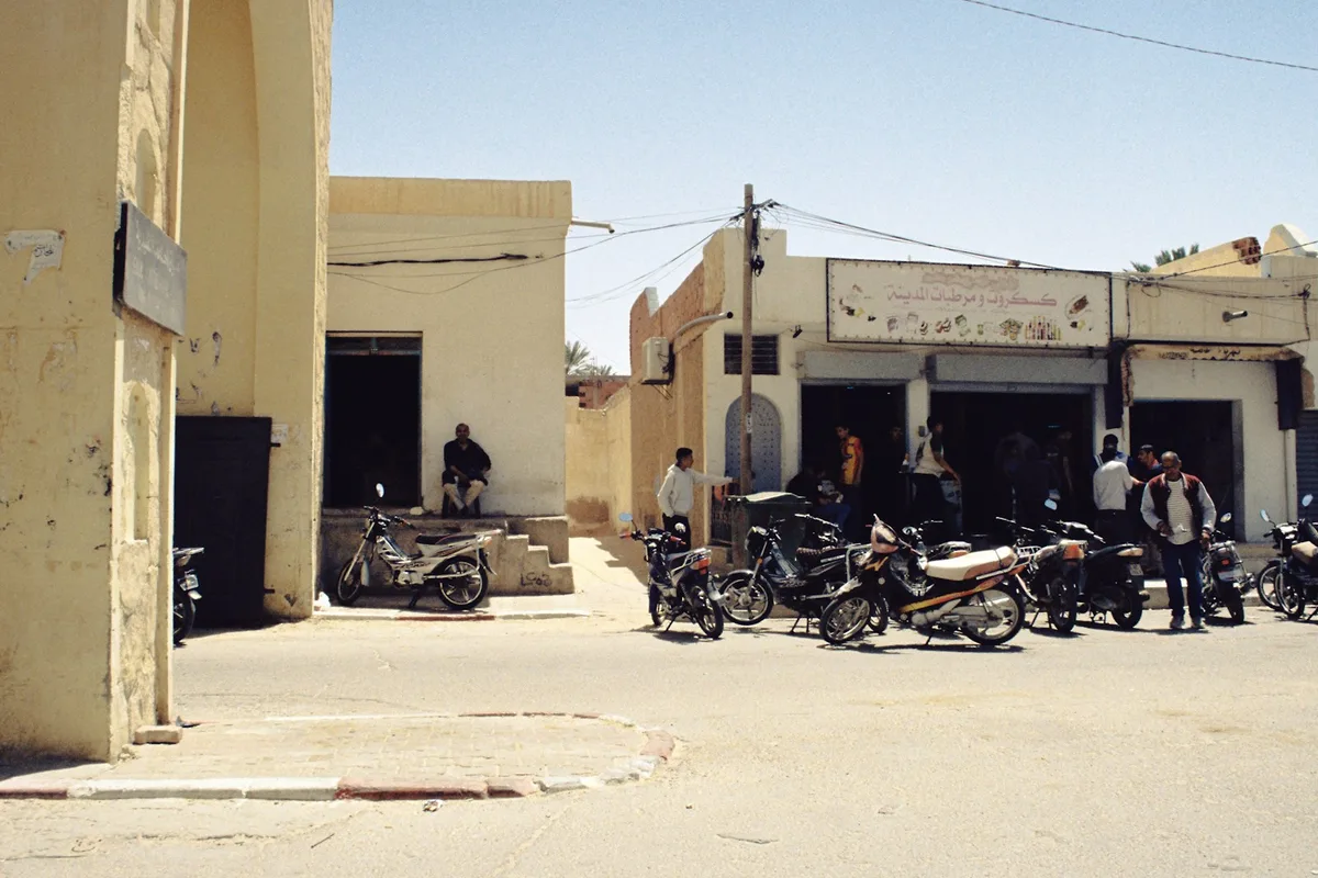 Motos garées devant les boutiques d'une rue commerçante tunisienne en pleine journée