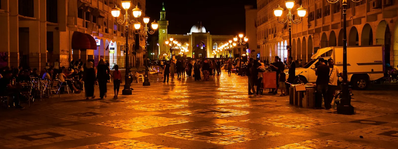 Avenue de la médina de Sfax éclairée en début de soirée, commerces ouverts