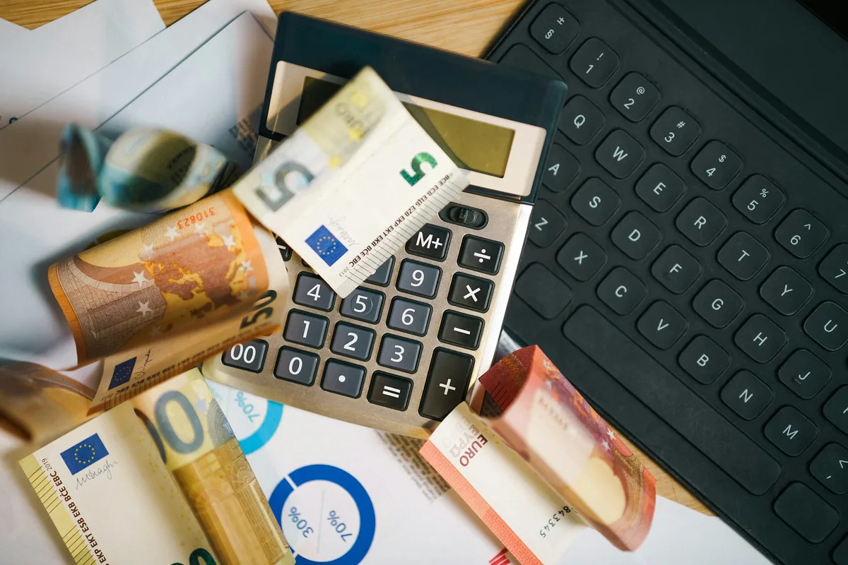 Calculatrice posée sur des billets en euros étalés sur un bureau