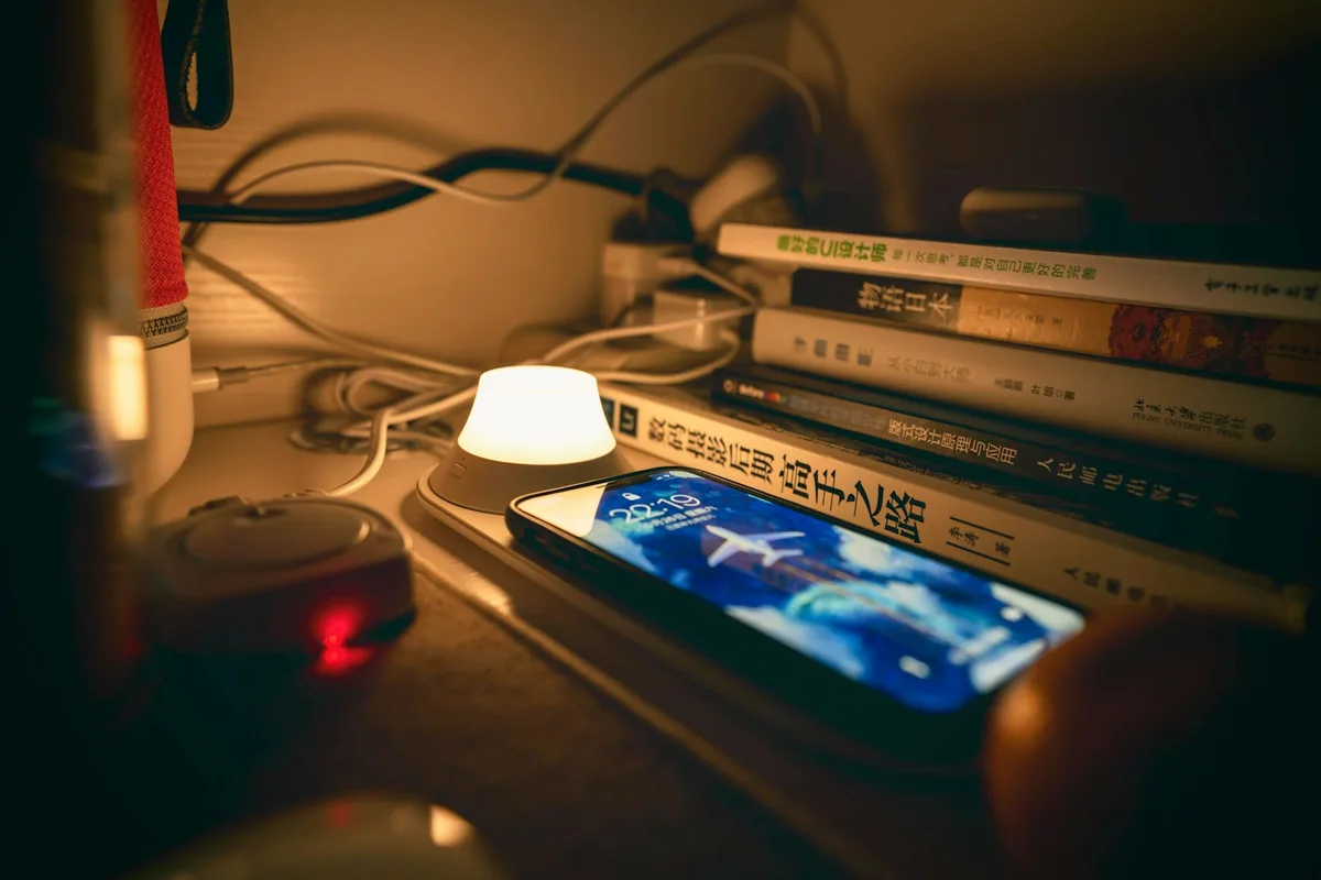 Téléphone allumé sur un bureau éclairé par une petite lampe, en fin de soirée