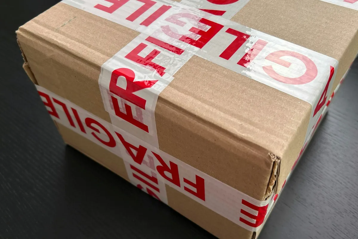 Un colis en carton fermé par un ruban fragile, prêt pour la livraison