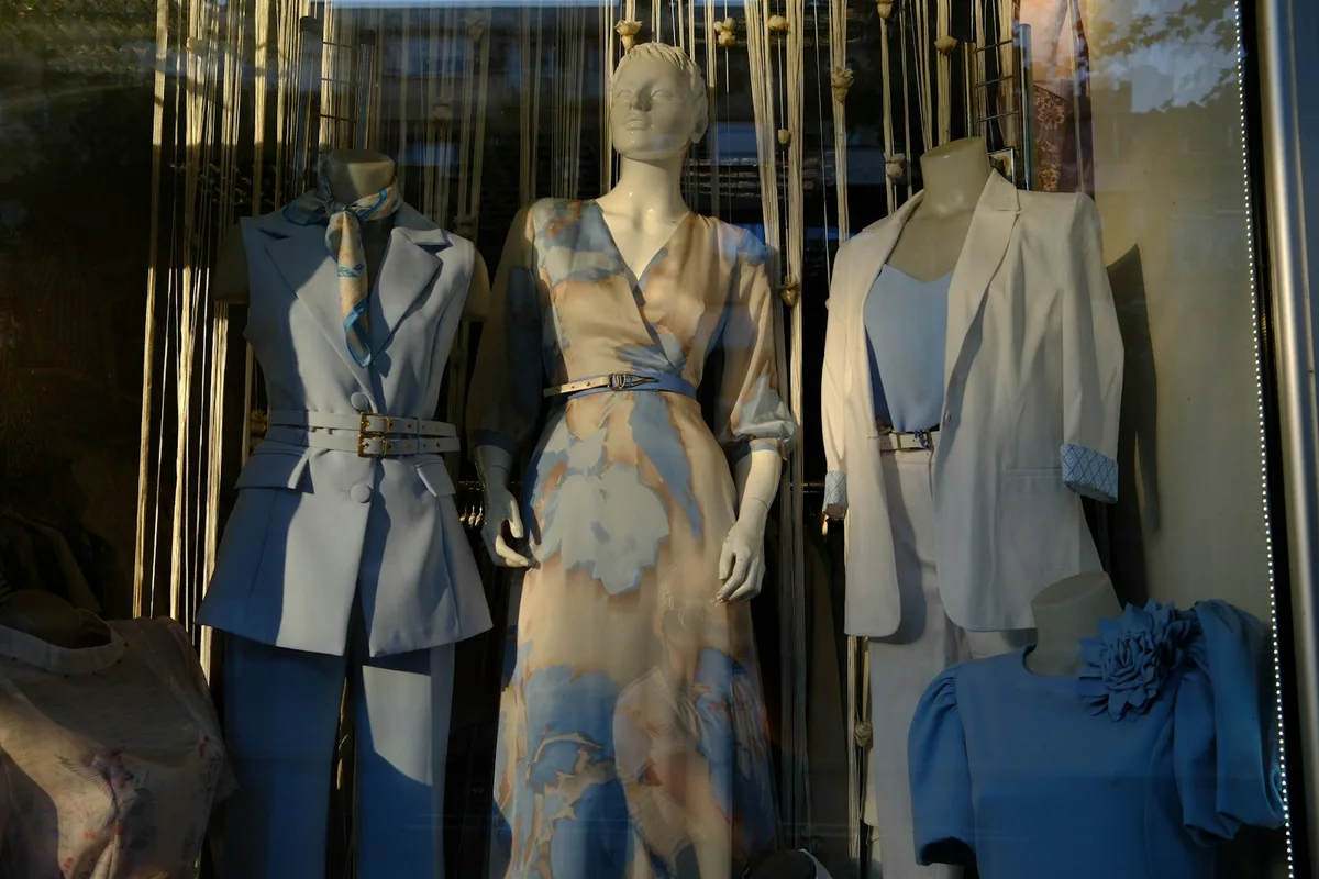 Vitrine de prêt-à-porter présentant une nouvelle collection sur trois mannequins éclairés