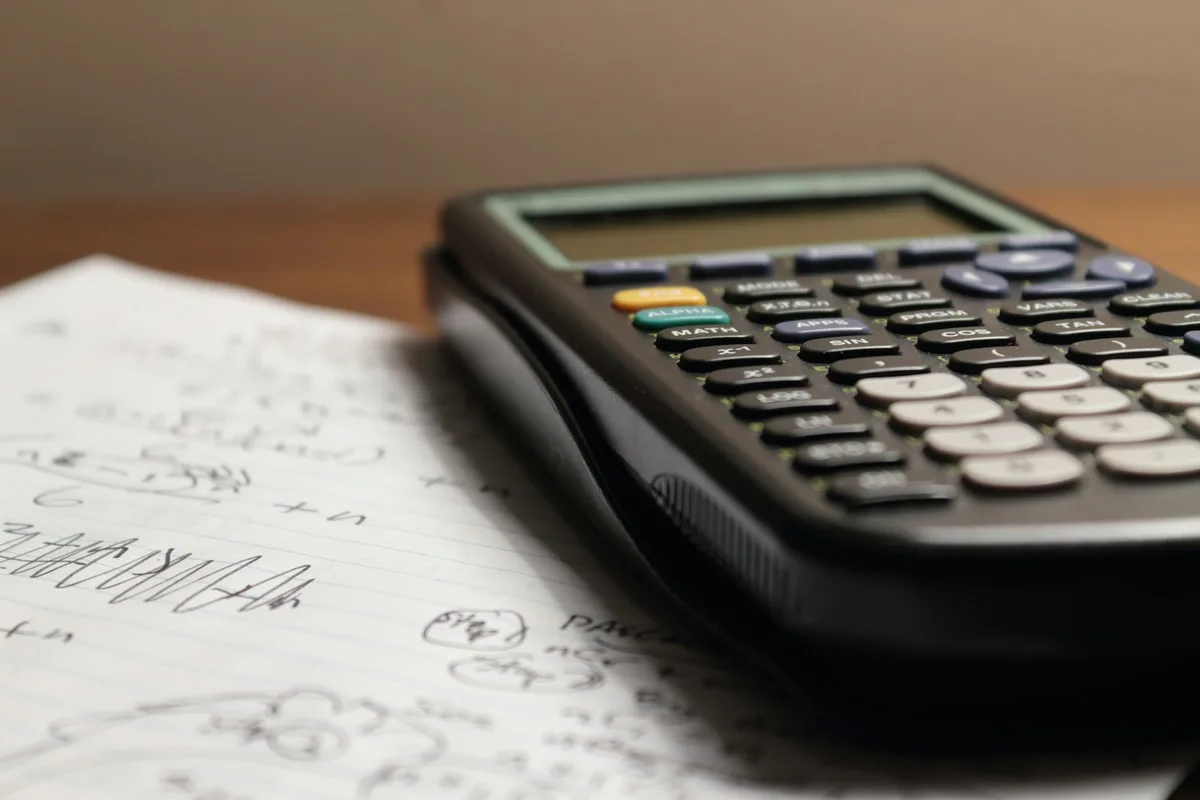 Carnet quadrillé ouvert sur un tableau tracé à la main avec une calculatrice à côté
